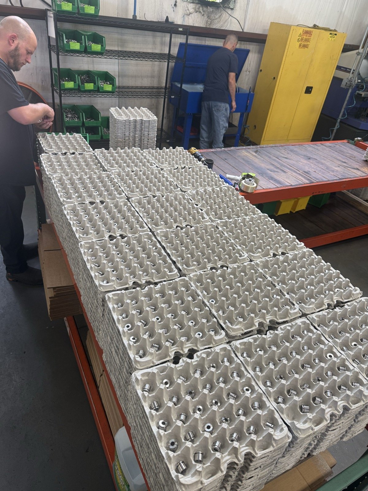 TXSwiss high-volume production run — operators packaging large quantity of precision Swiss CNC machined parts onto industrial trays for shipment