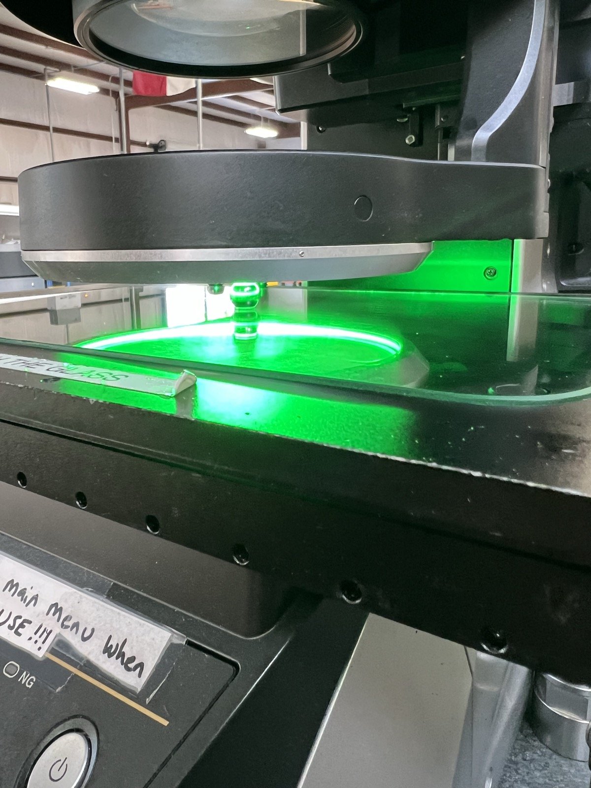 Close-up of TXSwiss Keyence optical comparator measurement under green LED light during precision part inspection