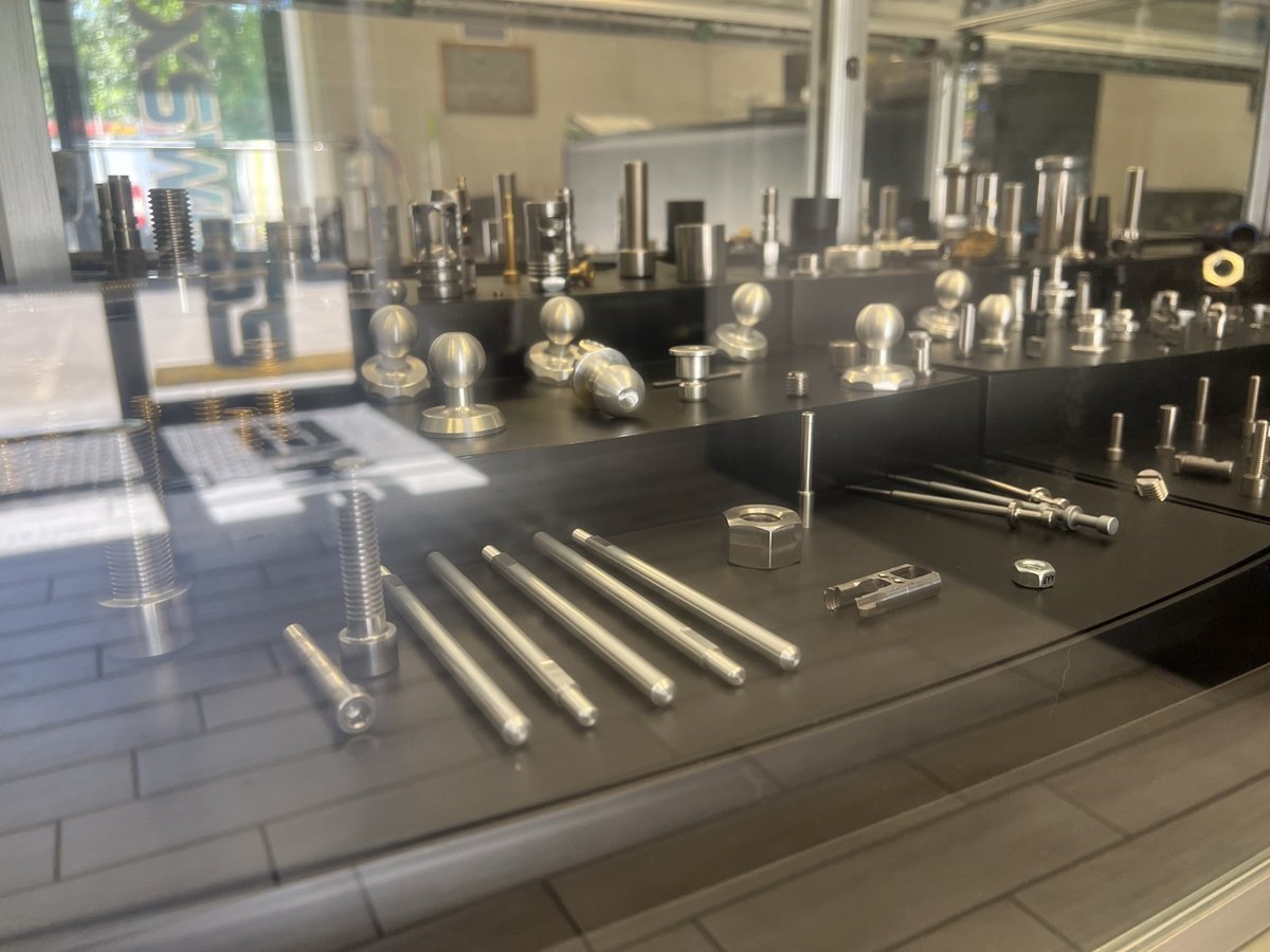Display case of TXSwiss-machined precision fittings, fasteners, and small components in stainless and brass
