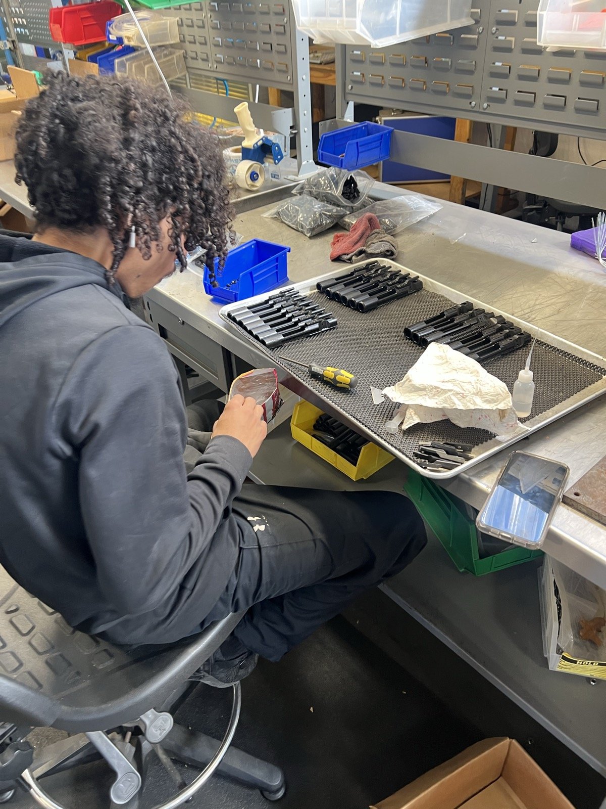 TXSwiss machinist inspecting tray of precision-machined pin and small-component parts at the Conroe, Texas quality control area