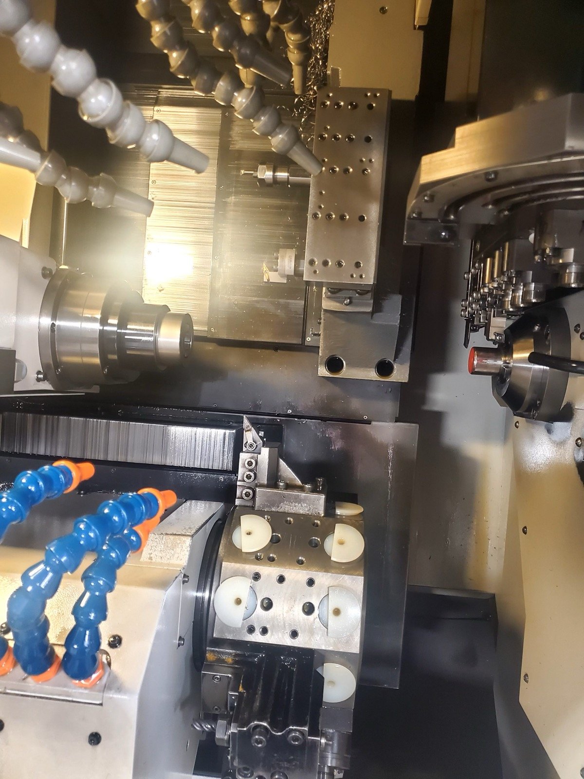 Inside view of a TXSwiss multi-axis Swiss CNC machine showing guide bushing, sub-spindle, and live tooling mid-cut on bar stock